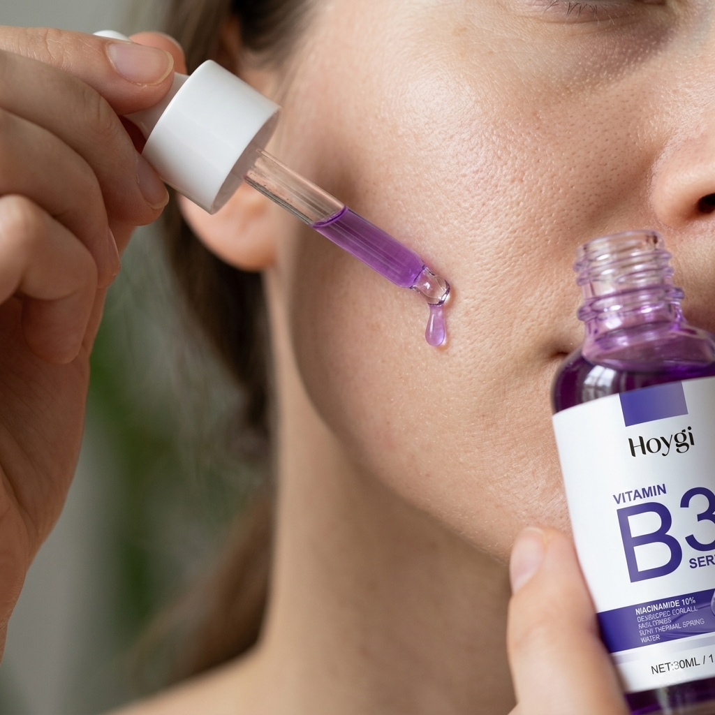 Close-up of a person applying purple niacinamide serum to their cheek using a dropper bottle